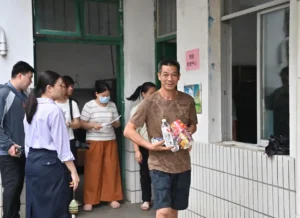 man carrying food suuplies walks away from a building with a line of people behind him